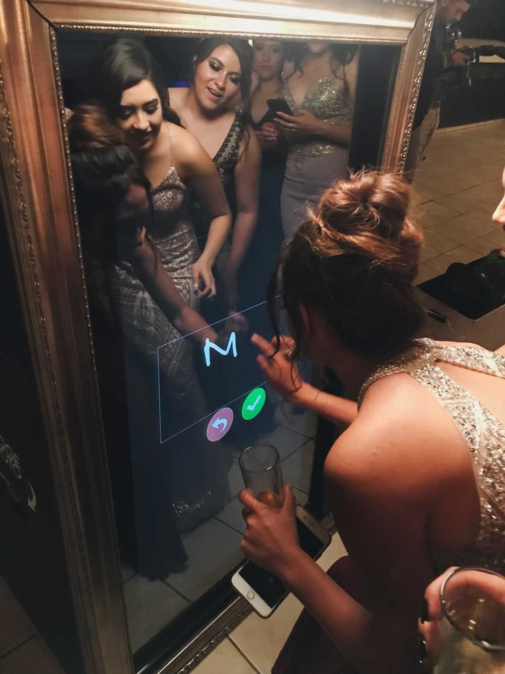 Invitadas firmando su foto en la pantalla táctil del espejo mágico durante una fiesta
