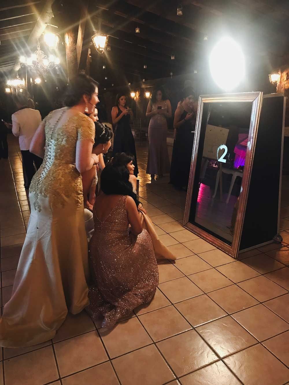 Invitadas en vestido de gala posando frente al espejo mágico en salón de Querétaro