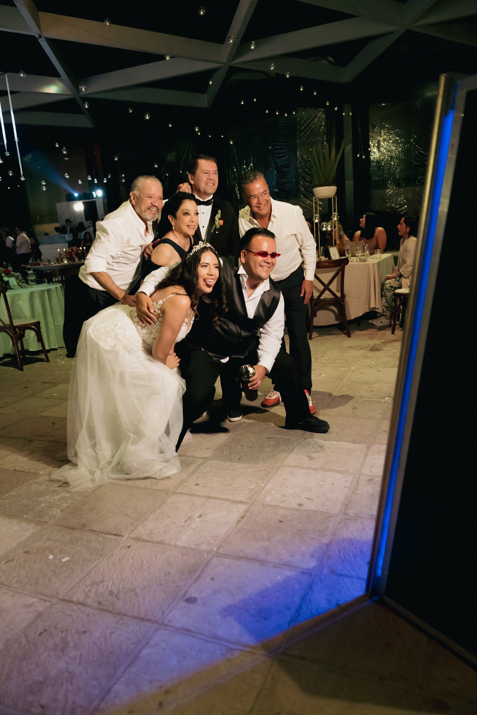Novia riendo con su familia mientras posan frente al espejo mágico Pikibooth en su boda en Querétaro